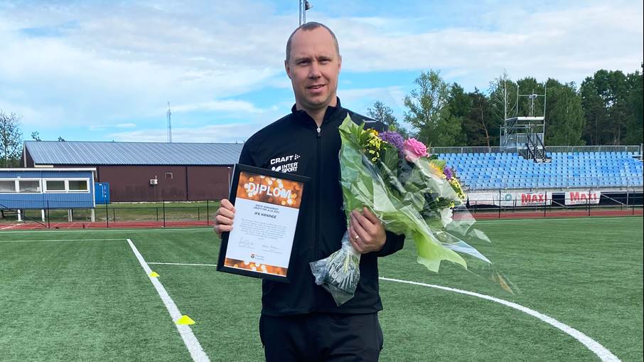 En person står med diplom och blommor.
