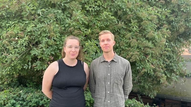 Mikael Lindblom tar över Rebecca Brivings roll under hennes föräldraledighet. Två personer framför en grön buske.