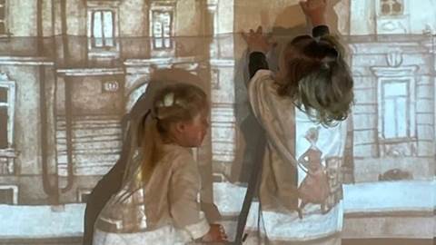 Två förskolebarn utforskat en bild som projiceras på en vägg.