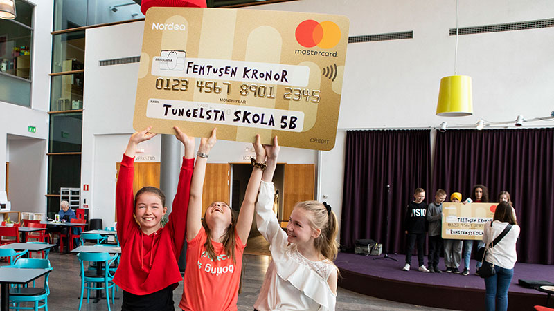 Vinnarna sträcker upp händerna med en check i handen.