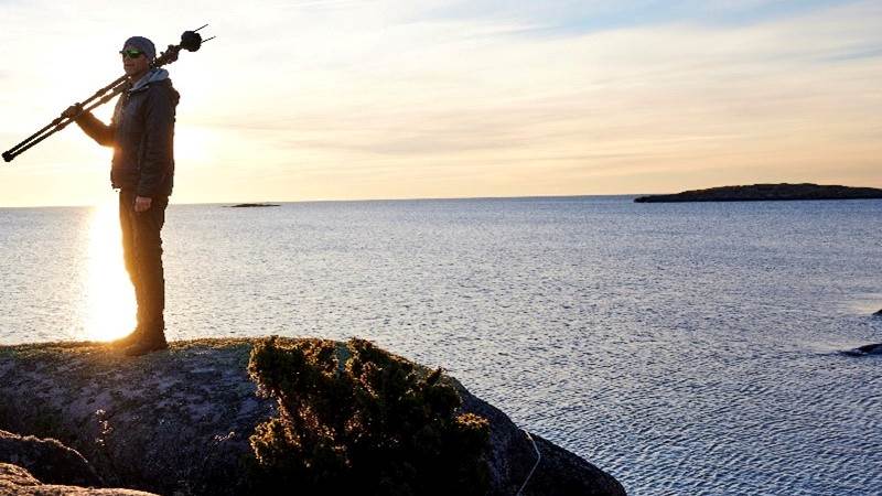 Man med kamerastativ på en klippa i skärgården