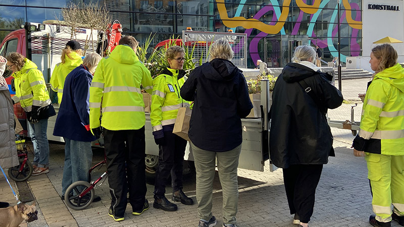 Medarbetare från Haninge kommun i gula jackor som delar ut blomsterkassar