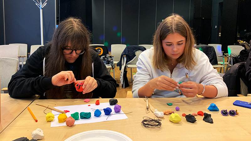 Hög koncentration under en kreativ workshop under ledning av Pedagogiska Designbyrån. Två tjejer gör monster av lera