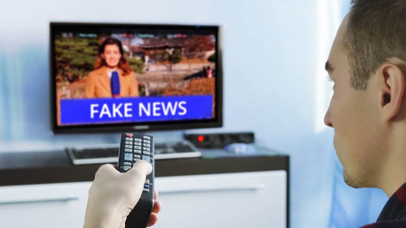 En man tittar på TV och ser på fejkade nyheter, så kallade fejk news