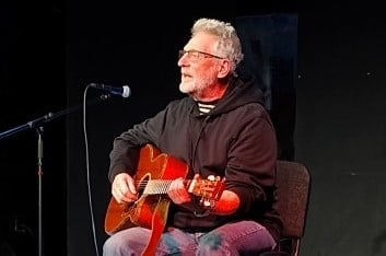 Lennart Harrysson spelar gitarr på en scen.