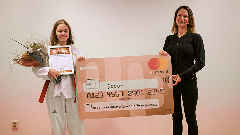 Tjej i taekwondo-klädsel tar emot prischeck.