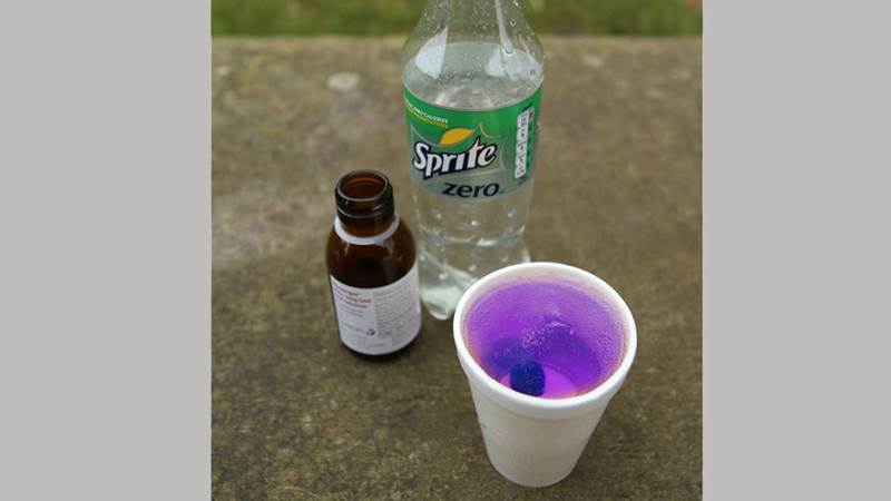 Hostmedicin blandas med läsk, oftast Sprite. En flaska med Sprite-läsk, en brun medecinflaska och en pappersmugg med lila vätska.
