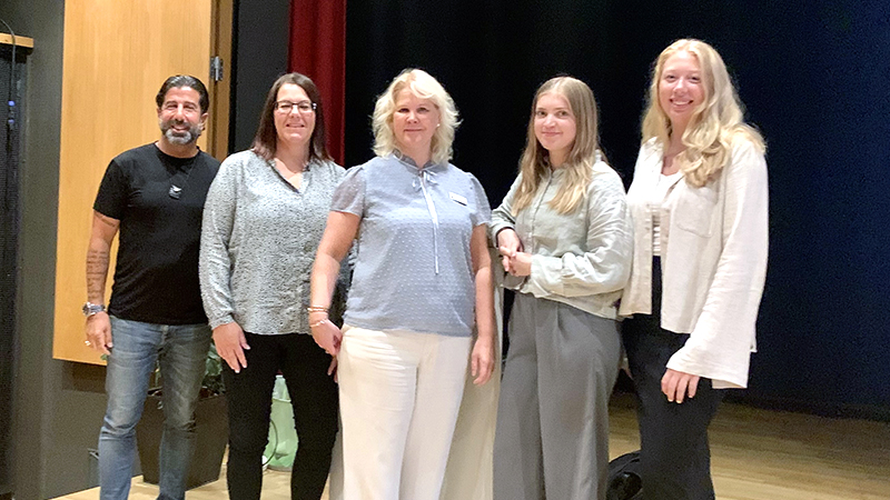 En man och fyra kvinnor står bredvid varandra i Fredrika Bremergymnasiets aula.