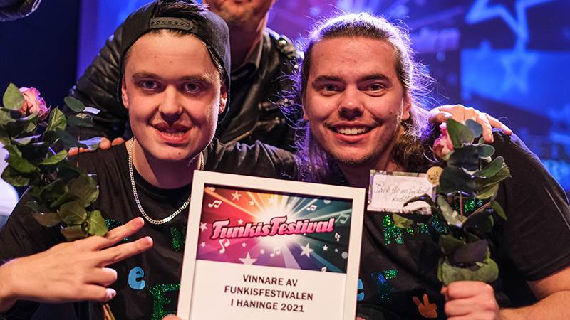 Anton Wallman och Niklas Martinsson vann Haninges delfinal i Funkisfestivalen. Vinnarna Anton Wallman och Niklas Martinsson ler mot kameran och visar upp sitt vinnardiplom samt håller i blommor.