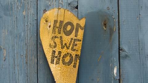 Ett trasigt trähjärta med texten "Home sweet home" hänger på en dörr