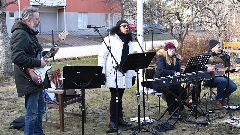 Karin Dietrichson med vänner. Fyra musikanter spelar instrument och sjunger utomhus.