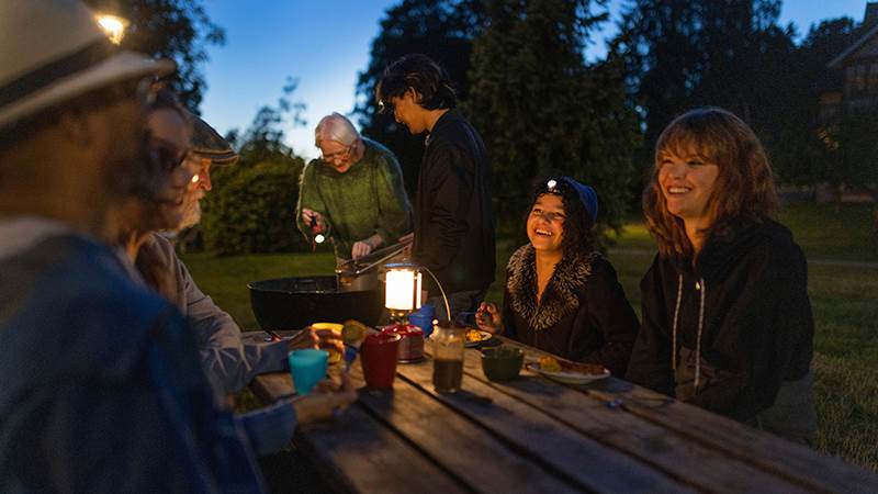 Grannar sitter tillsammans utomhus en mörk kväll.