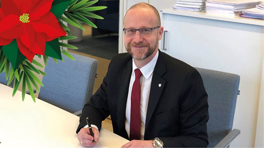 Kommundirektör Magnus Gyllestad Kommundirektör sitter framför ett skrivbord och skriver. En julros syns i övre vänstra hörnet