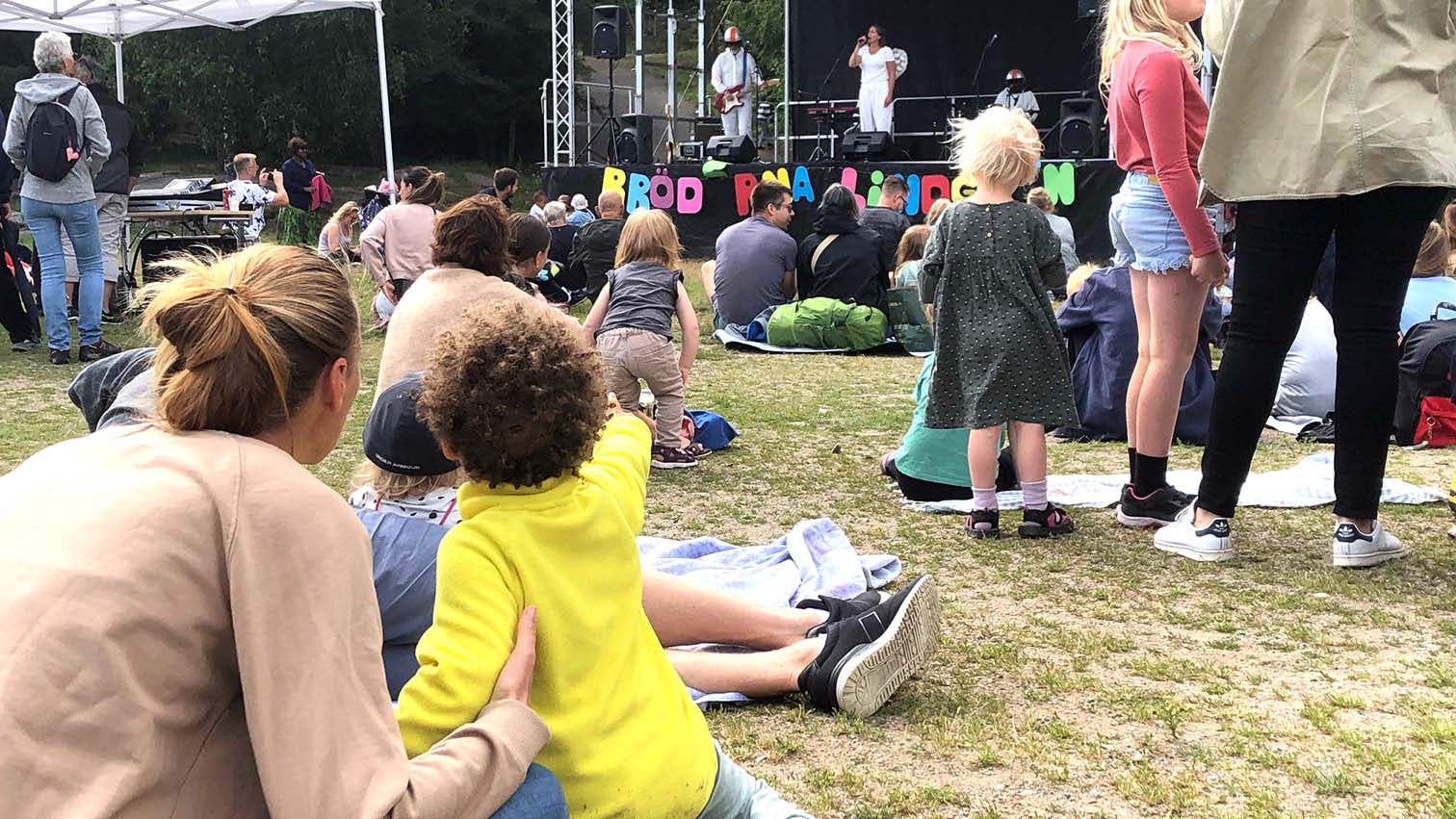 Människor sitter utomhus och tittar på en föreställning.