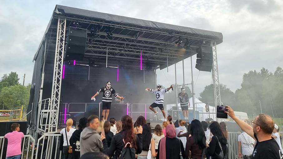 Ungdomar framför en scen där maskerade män uppträder.