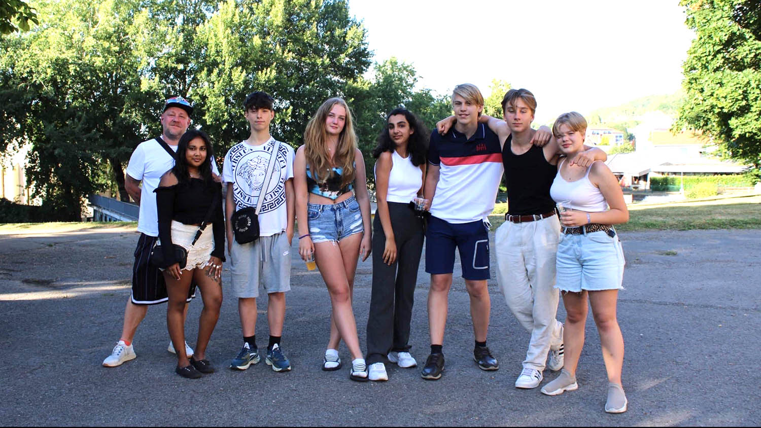 Ungdomar i sommarkläder står bredvid varandra utomhus.