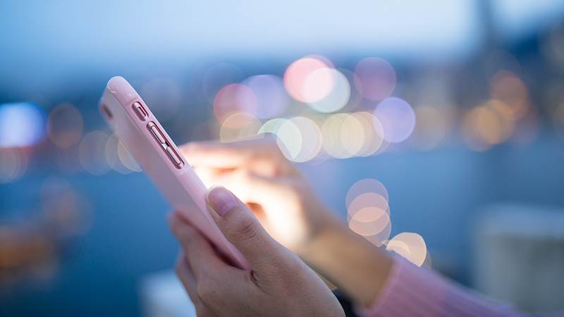 En kvinna håller i en rosa mobiltelefon