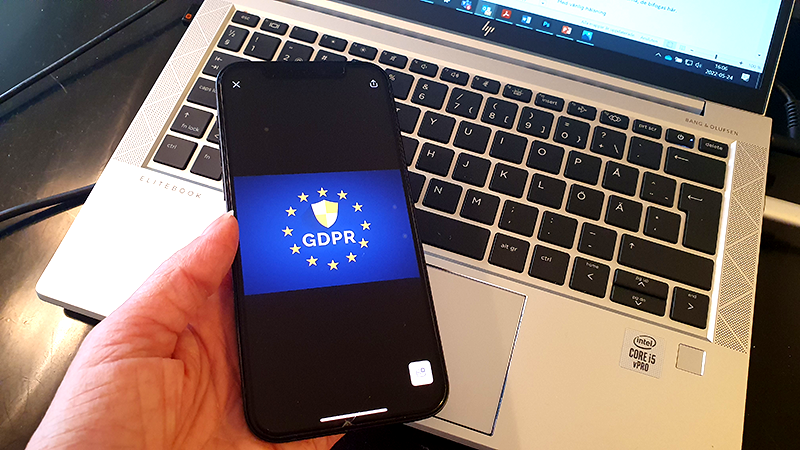 En person håller i en mobiltelefon där GDPR-logotypen syns