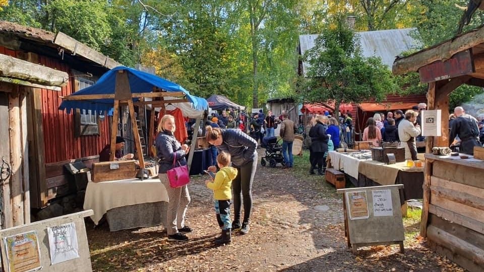 Besökare på en utomhusmarknad i höstmiljö.