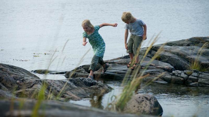 Längtan till hav och natur, till miljöombyte och gemenskap har lett till högtryck på Haninges turistanläggningar. En flicka och en pojke balanserar på stenar på vattnet.