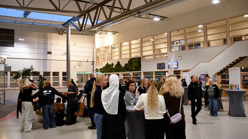 Översiktsbild från evenemanget med minglande deltagare i en ljus inomhusmiljö på Fredrika Bremergymnasiet med högt i tak och stora fönster.