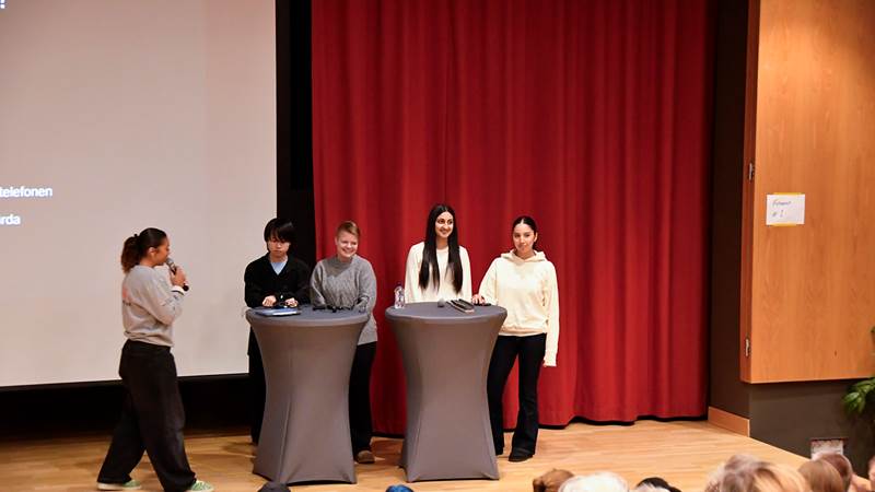 Paneldiskussion med moderatorn och fyra ungdomar på scen under föreläsningskvällen.