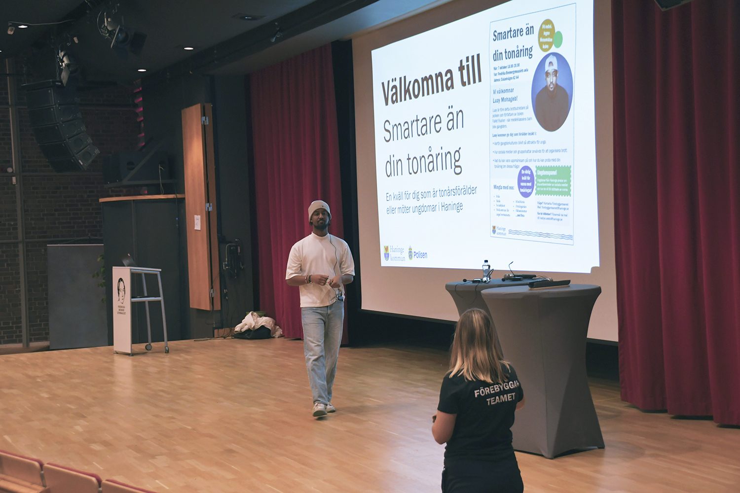 Föreläsaren är på scen och samtalar med en person från Förebyggarteamet.
