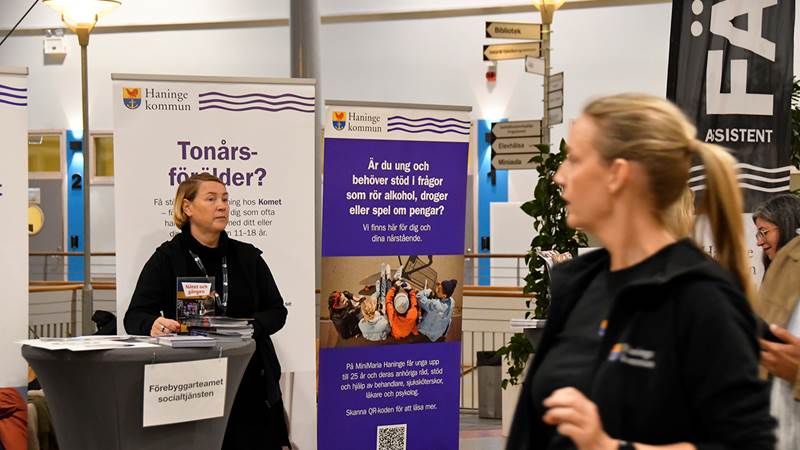 En person står i en informationsmonter från Haninge kommun med budskap riktade till tonårsföräldrar och unga som behöver stöd kring alkohol, droger eller spel.