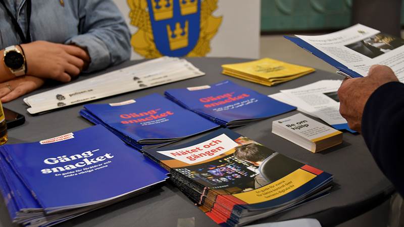 Uställningsbord hos Polisen med broschyrer och material om gängproblematik och nätbaserad påverkan, inklusive titlar som 'Gängsnacket' och 'Nätet och gängen'.