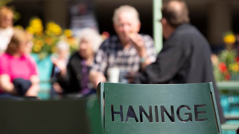 Text med Haninge i förgrunden och människor sittandes i bakgrunden