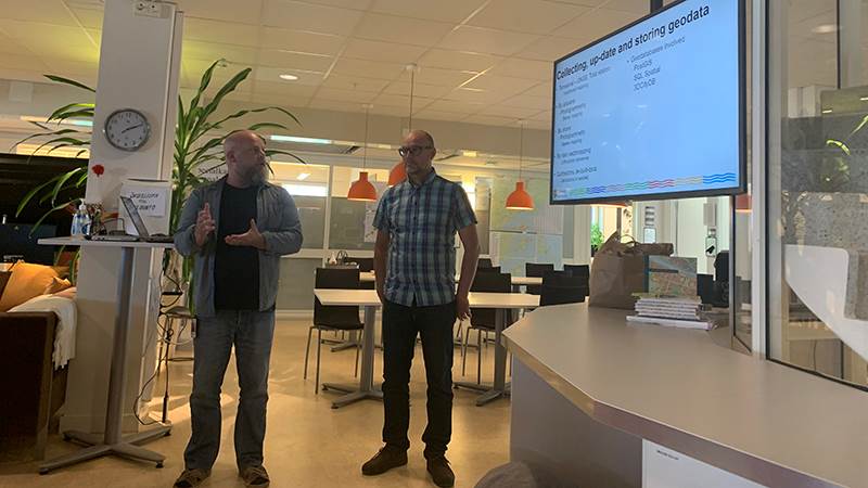 Två män i medelåldern står upp och håller en presentation.
