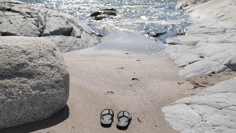 Badtofflor i sanden i vattenbrynet