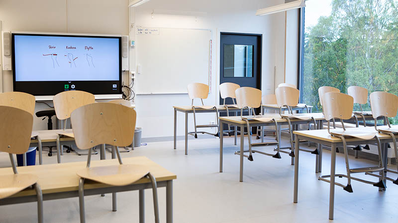 Stolar står uppställda på bord i ett tomt klassrum.