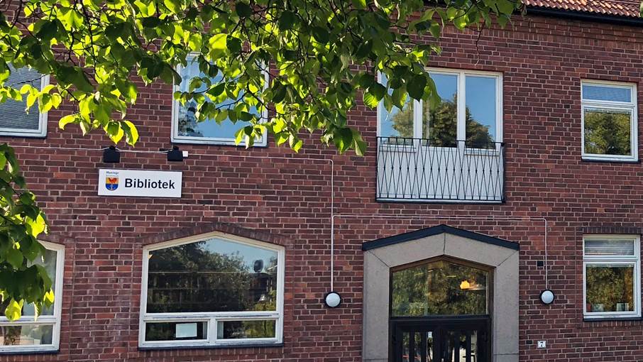 Tegelfasad med en skylt där det står bibliotek.