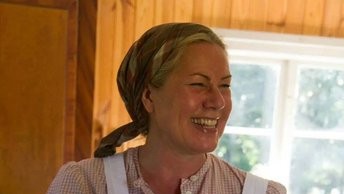 Kvinna som ler glatt under tiden hon bakar samiskt bröd