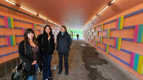 Personer som står tillsammans i en gångtunnel som är målad i aprikos-rosa färg