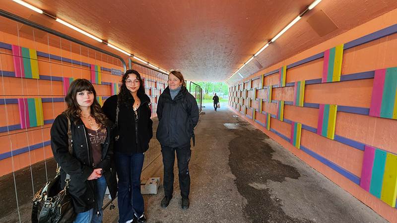 Personer som står tillsammans i en gångtunnel som är målad i aprikos-rosa färg