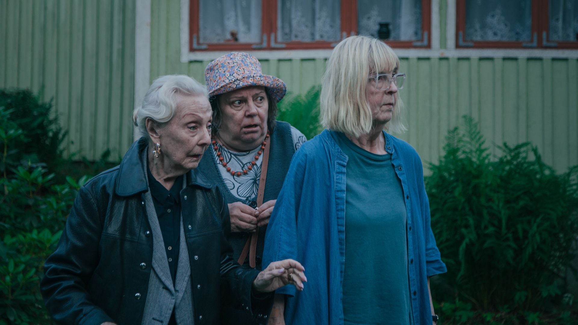 Tre kvinnor står bredvid varandra och tittar förvånat på något.