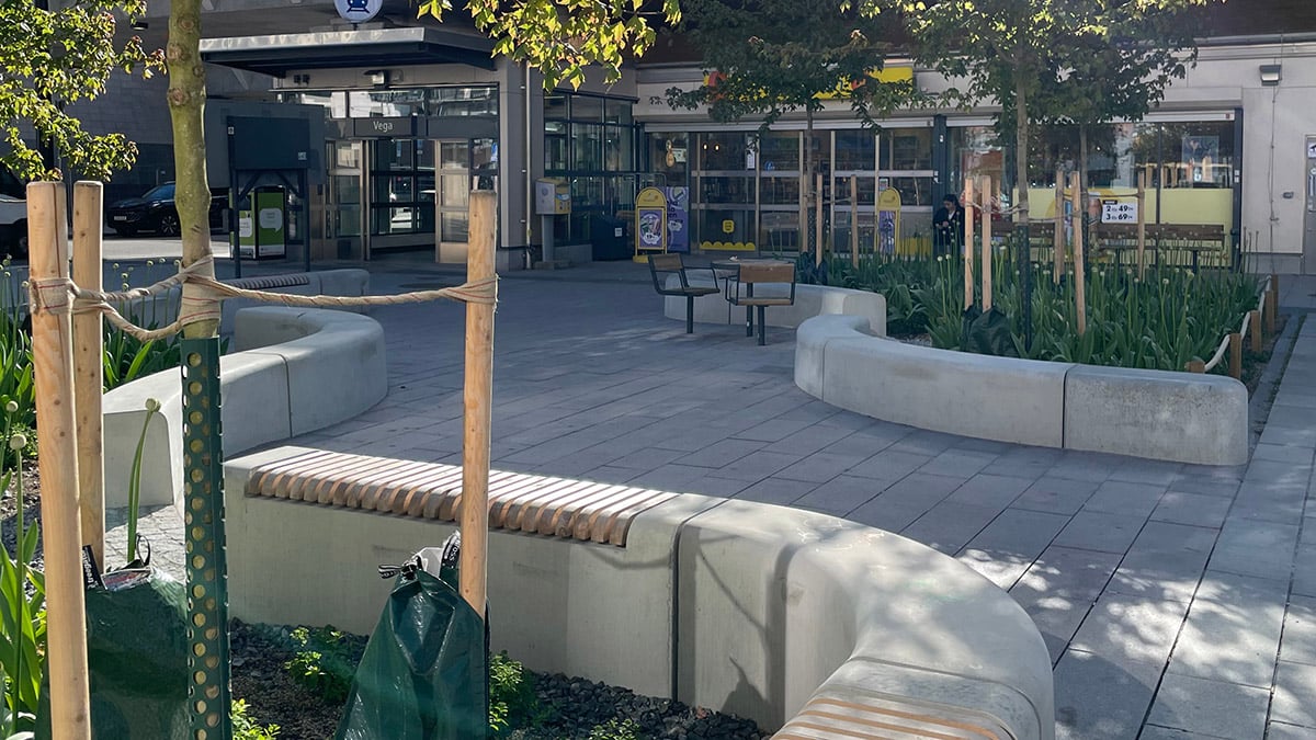 Stenlagt torg med slingrande sittplatser och grönska