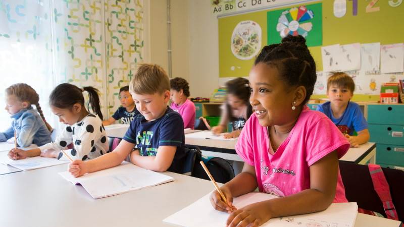 Skoldialog i Haninge kommun Barn sitter i sina skolbänkar och ler.