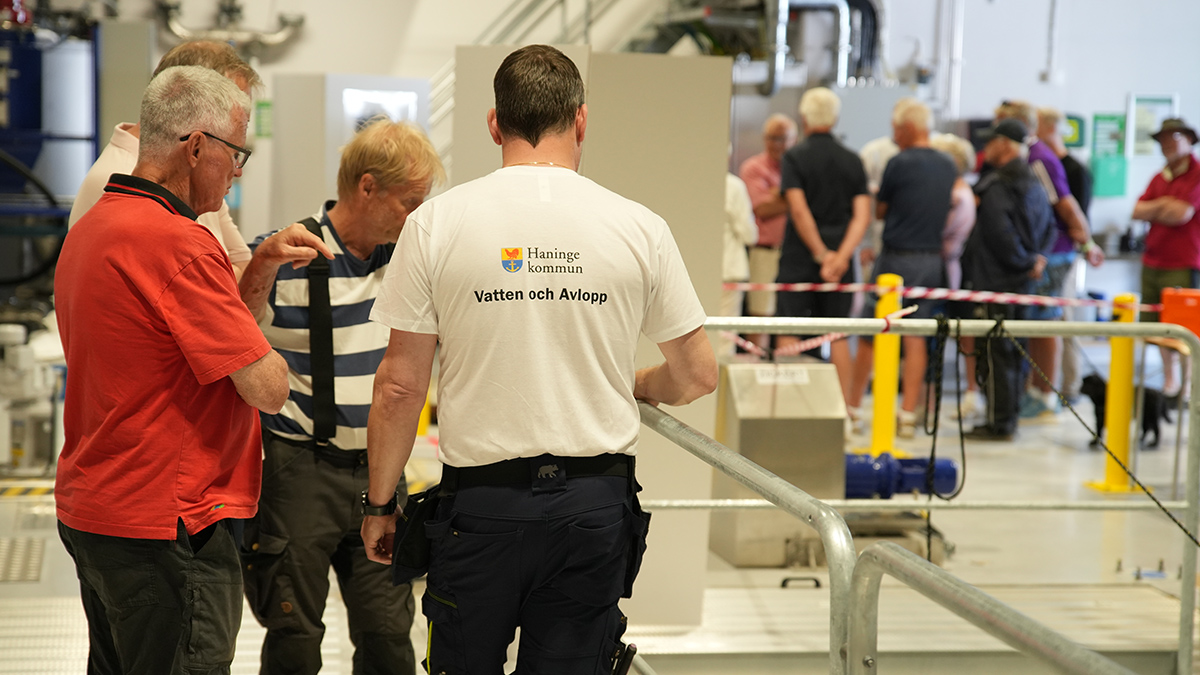 Personer i klunga som lyssnar på medarbetare från Haninge kommun