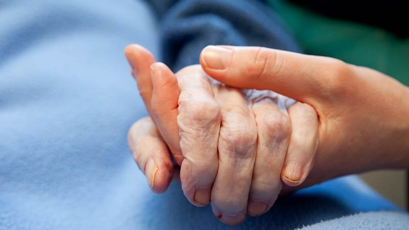 En ung och äldre människa håller i hand