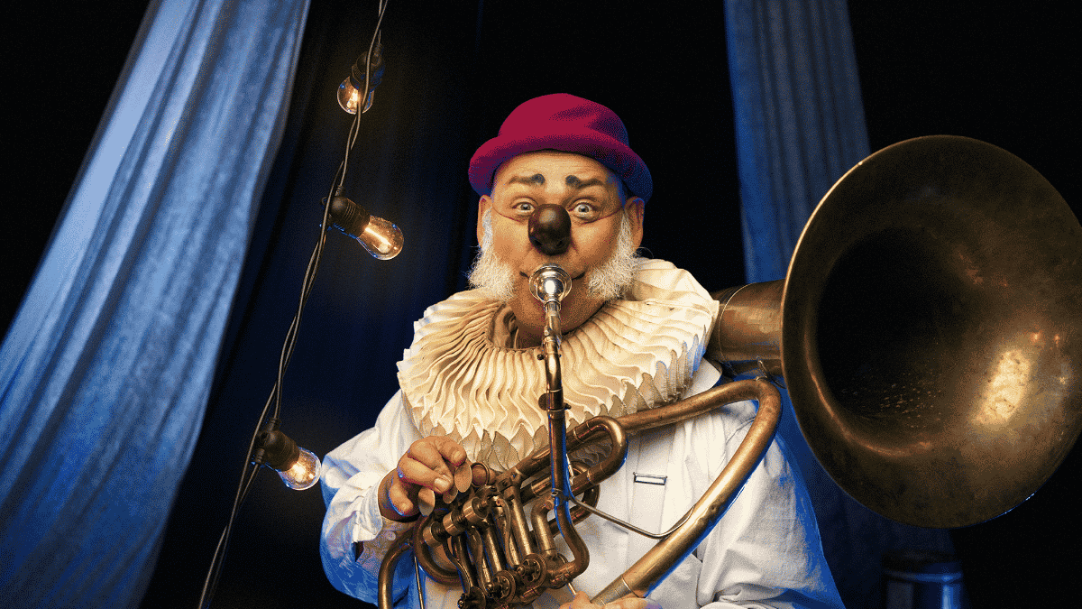 Clown med röd hatt och clownnäsa som blåser i instrument