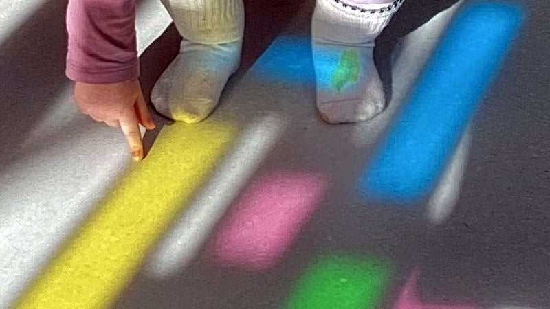 Skuggor i olika färger och ett barns hand som "känner" på skuggan.