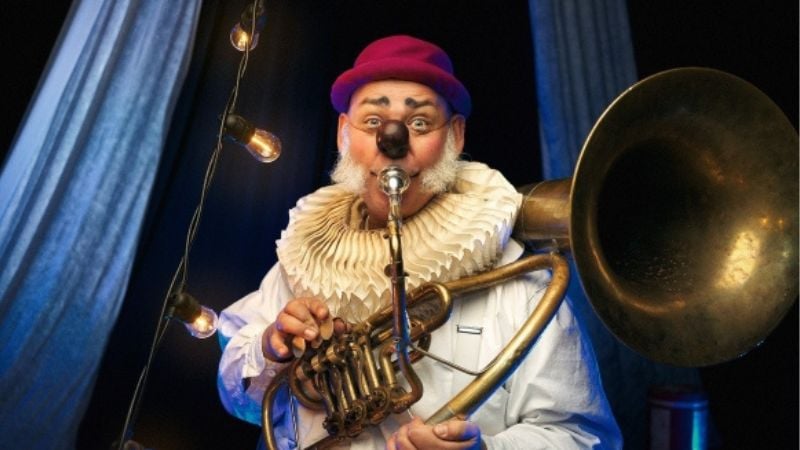 En clown med röd nästa spelar ett instrument.