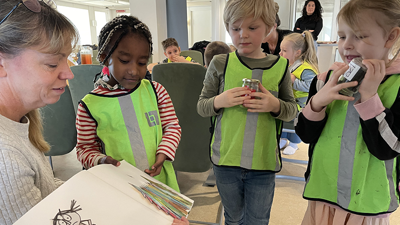 Pedagog visar bilder för tre barn i reflexvästar