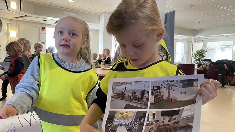 Två flickor i reflexvästar visar upp teckningar