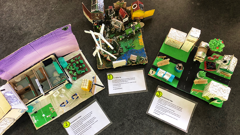 Tre pappersmodeller gjorda av återbruksmaterial fotade uppifrån