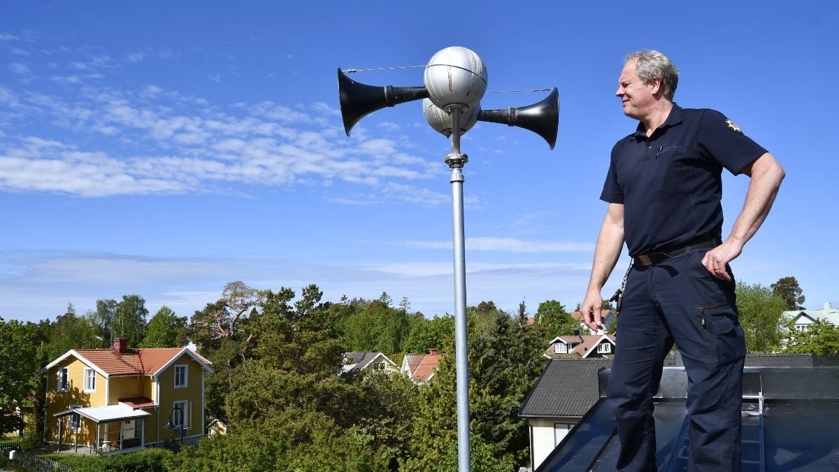 på stolpe på tak, med tekniker som står bredvid och inspekterar installationen.