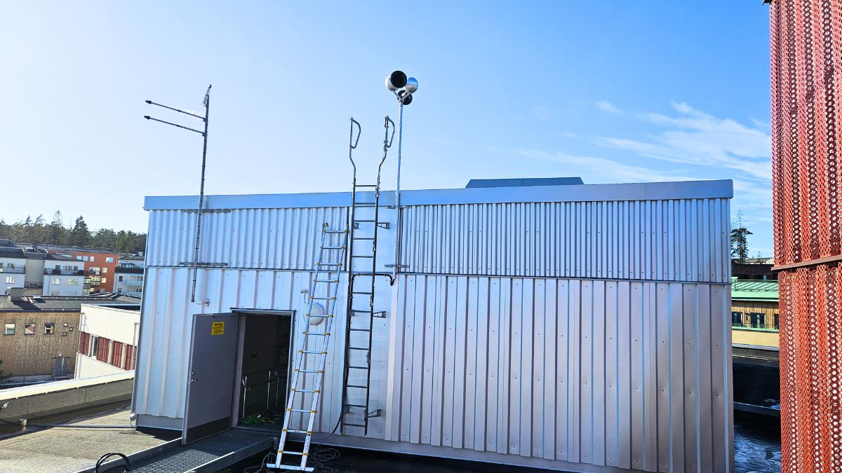 Tyfon installerad på tak till teknikbyggnad med stege och antenner.